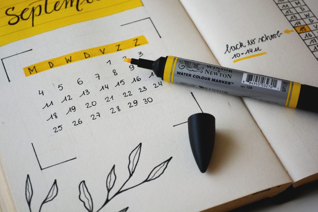 Handwritten calendar dates in a notebook with open yellow highlighter marker